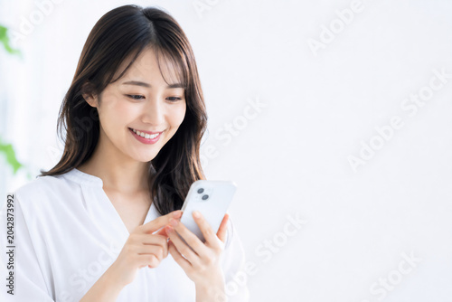 笑顔でスマートフォンを操作する若い日本人女性 Generative AI