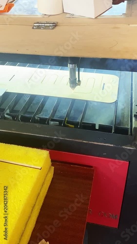 A laser machine cuts out plywood parts in a workshop