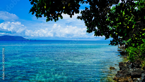 beautiful view of tropical beach with mountain backdrop and clear sky