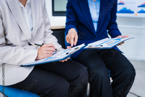 Foto Experienced Asian woman trains new employee in office work, teaching secretarial duties, document management, assistant manager responsibilities