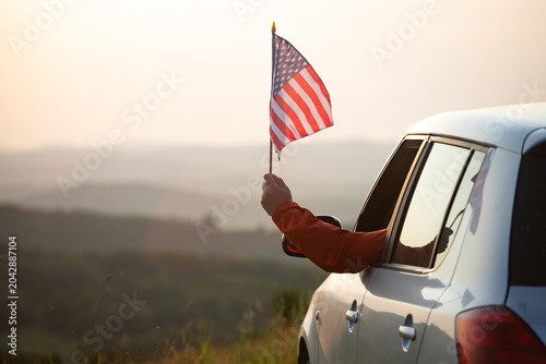 Fotografía Man in the car holding a waving american USA flag.