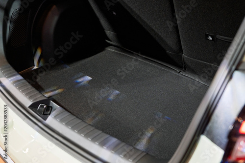 An angled close-up shot of the spacious, empty rear cargo trunk compartment of a modern vehicle