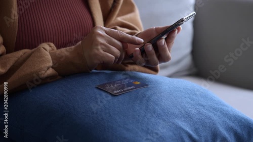 Asian mature woman using credit card booking ticket online on smartphone