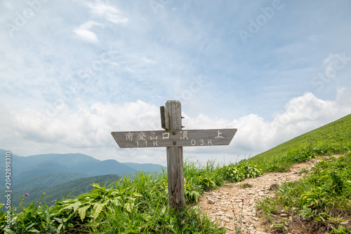 Wooden Hiking Signpost on a Mountain Trail Pointing Towards the Summit