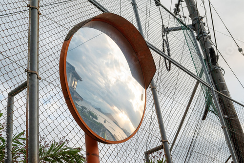 Tableau sur toile Scenic Sea and Sunset Sky Reflected in a Rusty Roadside Convex Traffic Mirror by
