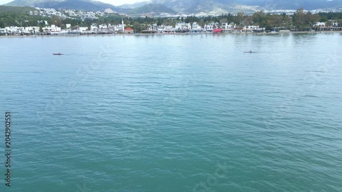 Aerial View of Rowing Race Competition in Turquoise Sea Near Coastal Hills. High quality 4k footage