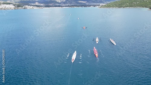 Aerial View of Professional Rowing Teams Competing in a Regatta near Scenic Coastal Town with Mountains. High quality 4k footage