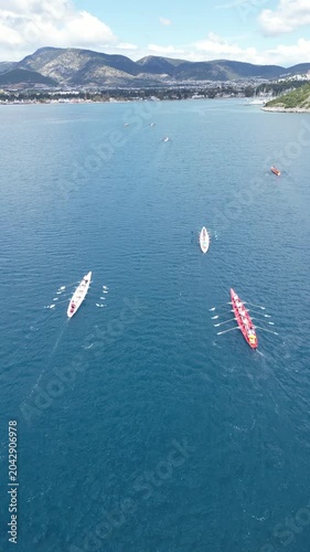 Aerial View of Professional Rowing Teams Competing in a Regatta near Scenic Coastal Town with Mountains. High quality 4k footage