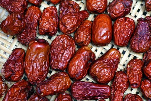 Close-up of dried red jujube fruits in a woven basket, showcasing natural texture, organic food preservation, and healthy agricultural produce.