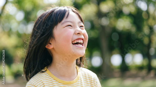 公園で空を見上げる可愛い女の子 芝生の上で笑顔