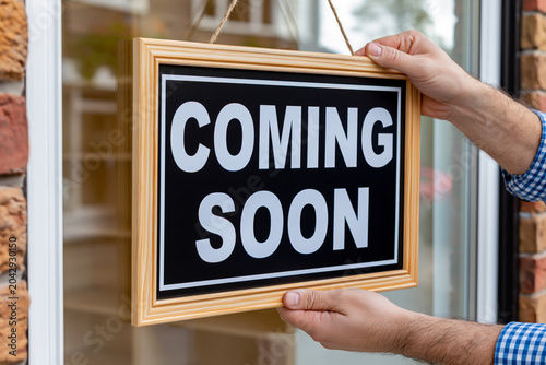Person hanging coming soon sign on storefront window