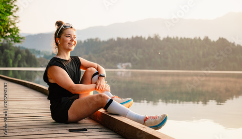 Woman running by the lake on a sunny day. Active lifestyle and outdoor fitness concept.
