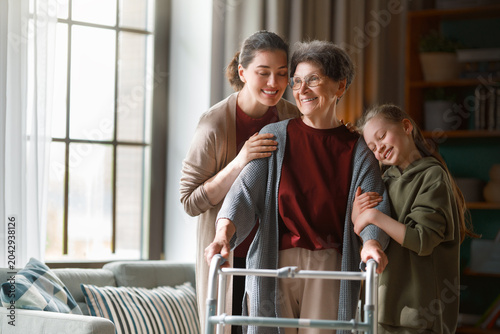 Картината върху платно Three Generations of Women Smiling Together, Senior with Walker at Home