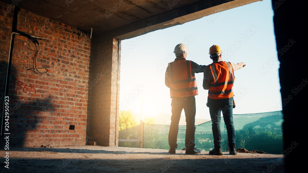 Fototapeta premium Back, people and engineer talking for construction, planning design and safety compliance. Men, meeting and pointing for quality assurance, building development and brainstorming for architecture