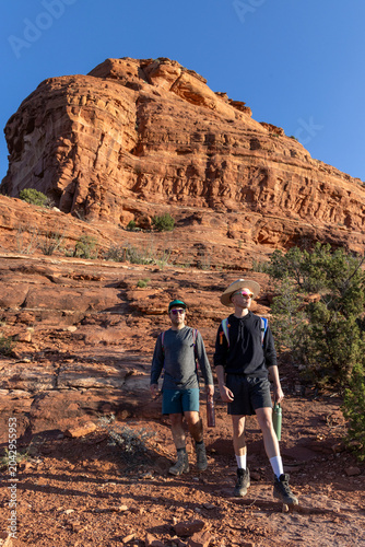Two male friends hike together in a desert canyon