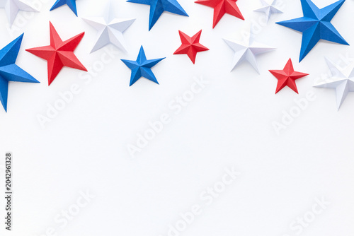 Red, white and blue origami paper stars on white background with large copy space, ideal for patriotic advertising, holiday promotions, greeting cards, invitations, banners, posters, social media