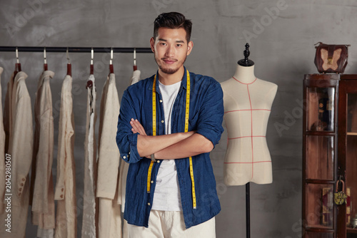 Bild auf Leinwand Confident Young Fashion Designer in Tailoring Studio