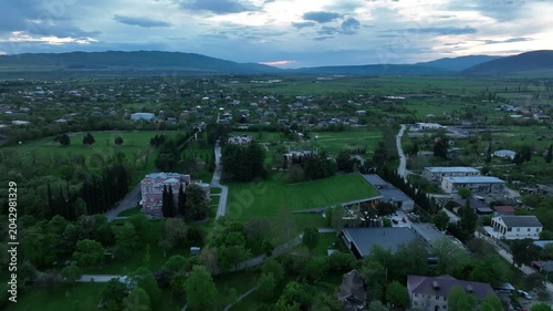 Aerial view of Chateau Mukhrani royal palace and estate in Georgia, magnificent pink castle architecture with a tower surrounded by a lush green park, gardens and pathways on a spring day.
