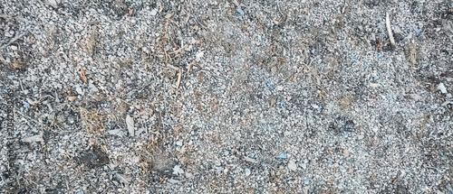 High-angle background shot of natural grey crushed stone aggregate mixed with dry organic debris, dirt, and small twigs. Perfect for construction, landscaping, gardening, or textured abstract backgrou
