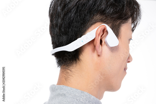 Bild auf Leinwand Young man wearing white bone conduction headphones in side view