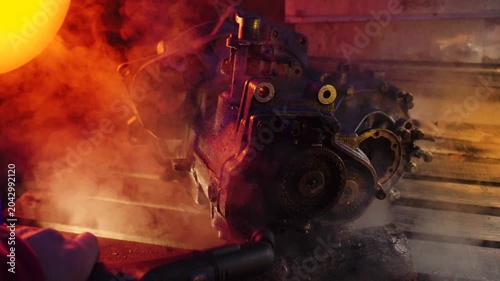 cleaning and washing with a steam cleaner of an old manual transmission from a front-wheel drive car for repair evening video shooting with red and purple lighting