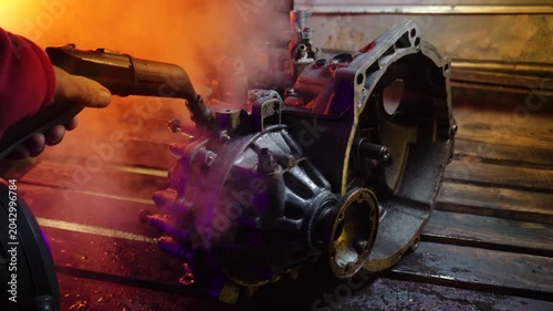 cleaning and washing with a steam cleaner of an old manual transmission from a front-wheel drive car for repair evening video shooting with red and purple lighting