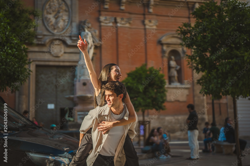 Obraz premium Happy joyful couple enjoying piggyback ride in city