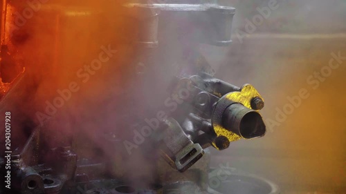 cleaning and washing with a steam cleaner of an old manual transmission from a front-wheel drive car for repair evening video shooting with red and purple lighting