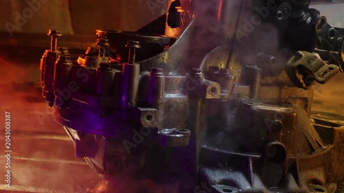 cleaning and washing with a steam cleaner of an old manual transmission from a front-wheel drive car for repair evening video shooting with red and purple lighting