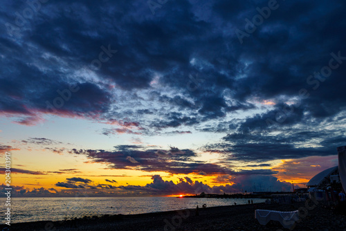 cenic shot of sea under dark dramatic clouds during bright sunset