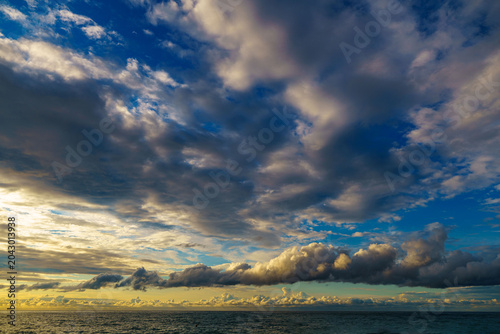 cenic shot of sea under dark dramatic clouds during bright sunset