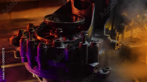 cleaning and washing with a steam cleaner of an old manual transmission from a front-wheel drive car for repair evening video shooting with red and purple lighting