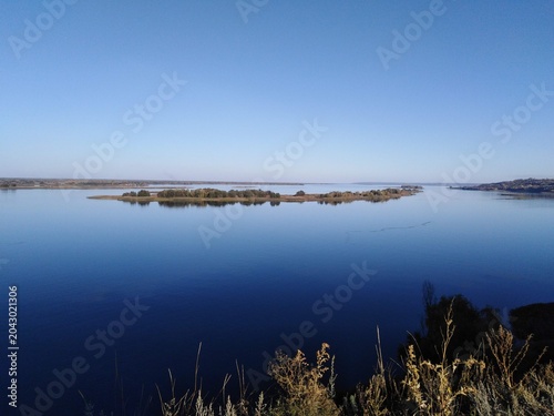 Foto scenic panoramic view of wide blue river with green island under clear sky