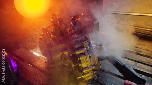cleaning and washing with a steam cleaner of an old manual transmission from a front-wheel drive car for repair evening video shooting with red and purple lighting