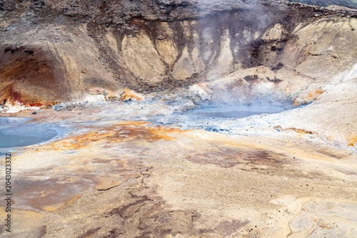 Boiling steam rises from the hot spring pools of the Seltun geothermal area in Iceland on a spring day.