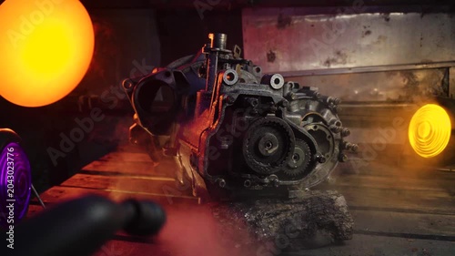 cleaning and washing with a steam cleaner of an old manual transmission from a front-wheel drive car for repair evening video shooting with red and purple lighting