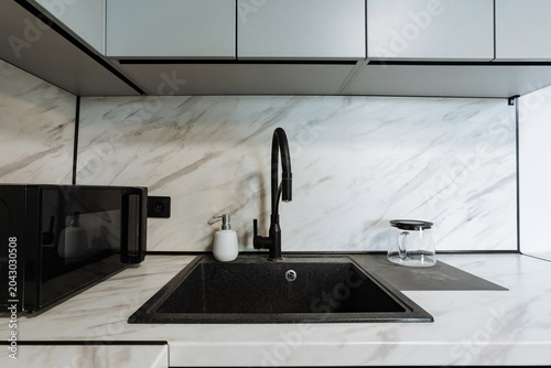 Tableau sur toile Modern kitchen countertop with built-in sink, black faucet, and minimalist desig