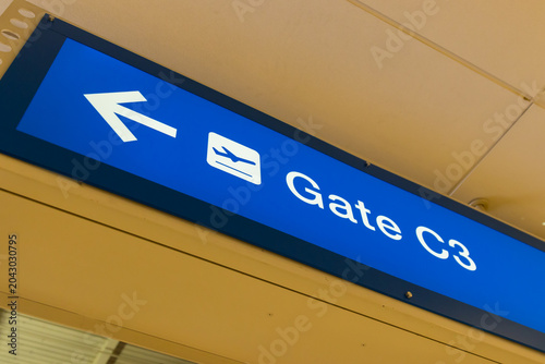 A blue sign hanging on the ceiling of an airport with an arrow to Gate C3