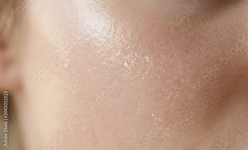 Close up of human skin texture with clear serum or gel drops