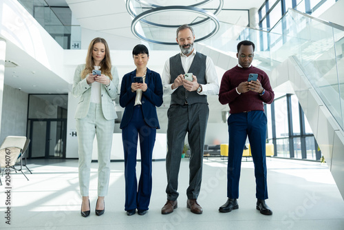 фотографія Four multiethnic business colleagues standing in contemporary office lobby, conn