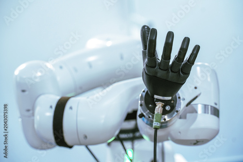 An anthropomorphic multi-jointed robotic hand attachment is displayed on an automated mechanical arm, highlighting advanced developments in cybernetics, prosthetics, and industrial automation.