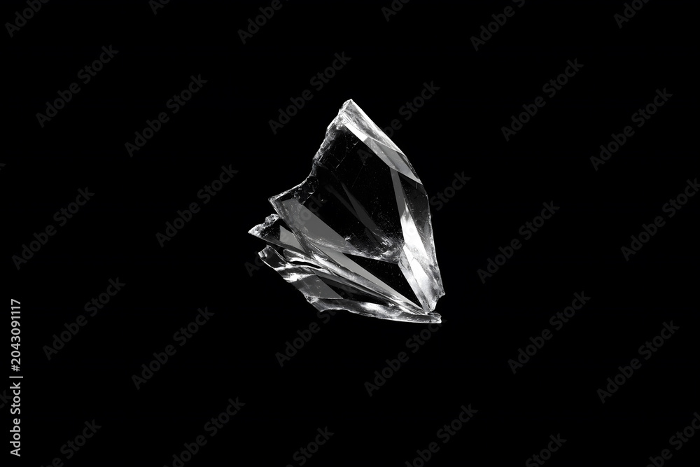 Naklejka premium Flying broken glass shards isolated on a black background, with sharp transparent fragments, glossy reflections, and dramatic studio lighting.
