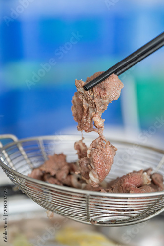 Foto Chopsticks picking up blanched Chaoshan fresh beef hot pot ingredients