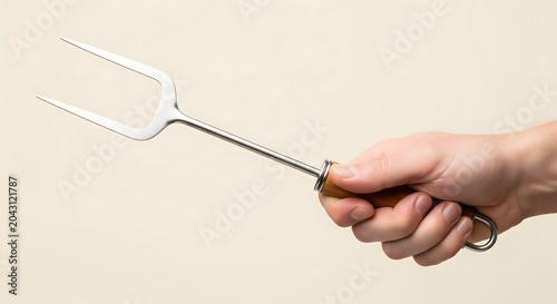 Hand holding a stainless steel carving fork for barbecue and kitchen use