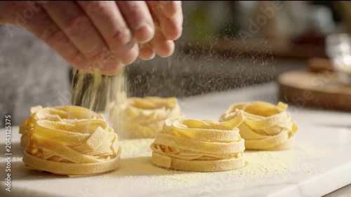 Close-Up of Hands Dusting Flour over Fresh Tagliatelle Pasta Nests