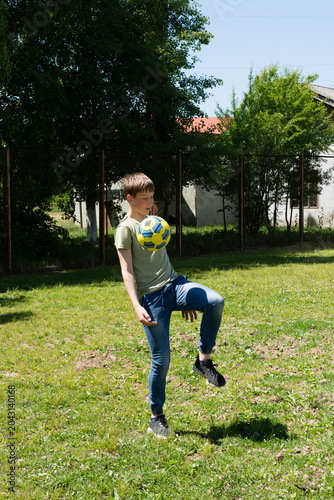 Teenager juggling soccer ball outdoors on sunny day. Active, playful summer scene.