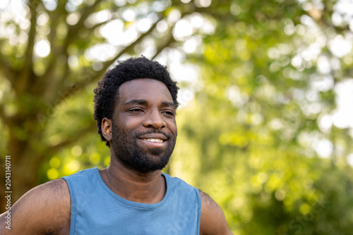 Smiling african man enjoying peaceful outdoor exercise in a lush green park, embracing wellness and a healthy, active lifestyle while breathing fresh air and feeling content