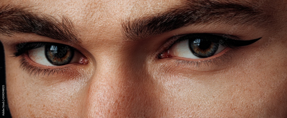 Naklejka premium Intense close-up portrait of a man with sharp eyeliner and piercing gaze conveying deep emotion