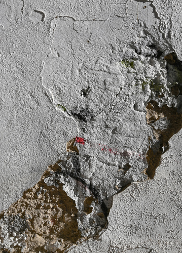 Cracked wall with peeling paint and rough texture in an indoor setting during daylight hours