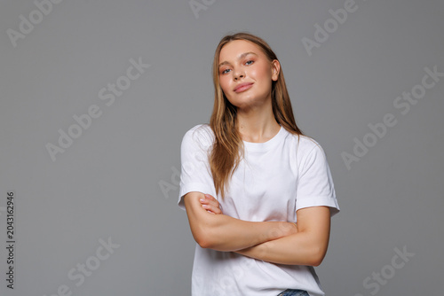 Young woman smiling and crossing her arms looking like a boss on white background